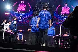 A professional esports team sitting side-by-side at a tournament stage playing a match